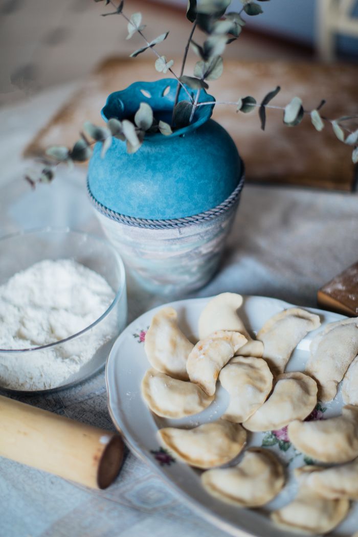 A cozy still life of homemade dumplings with flour and a decorative vase.