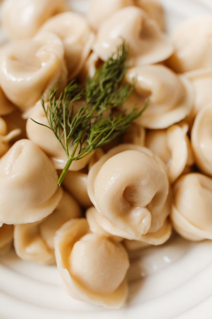 Delicious Russian pelmeni dumplings garnished with fresh dill, showcasing a close-up view.